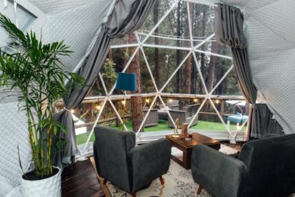 Elegant glamping dome with forest view and cozy interior seating area.